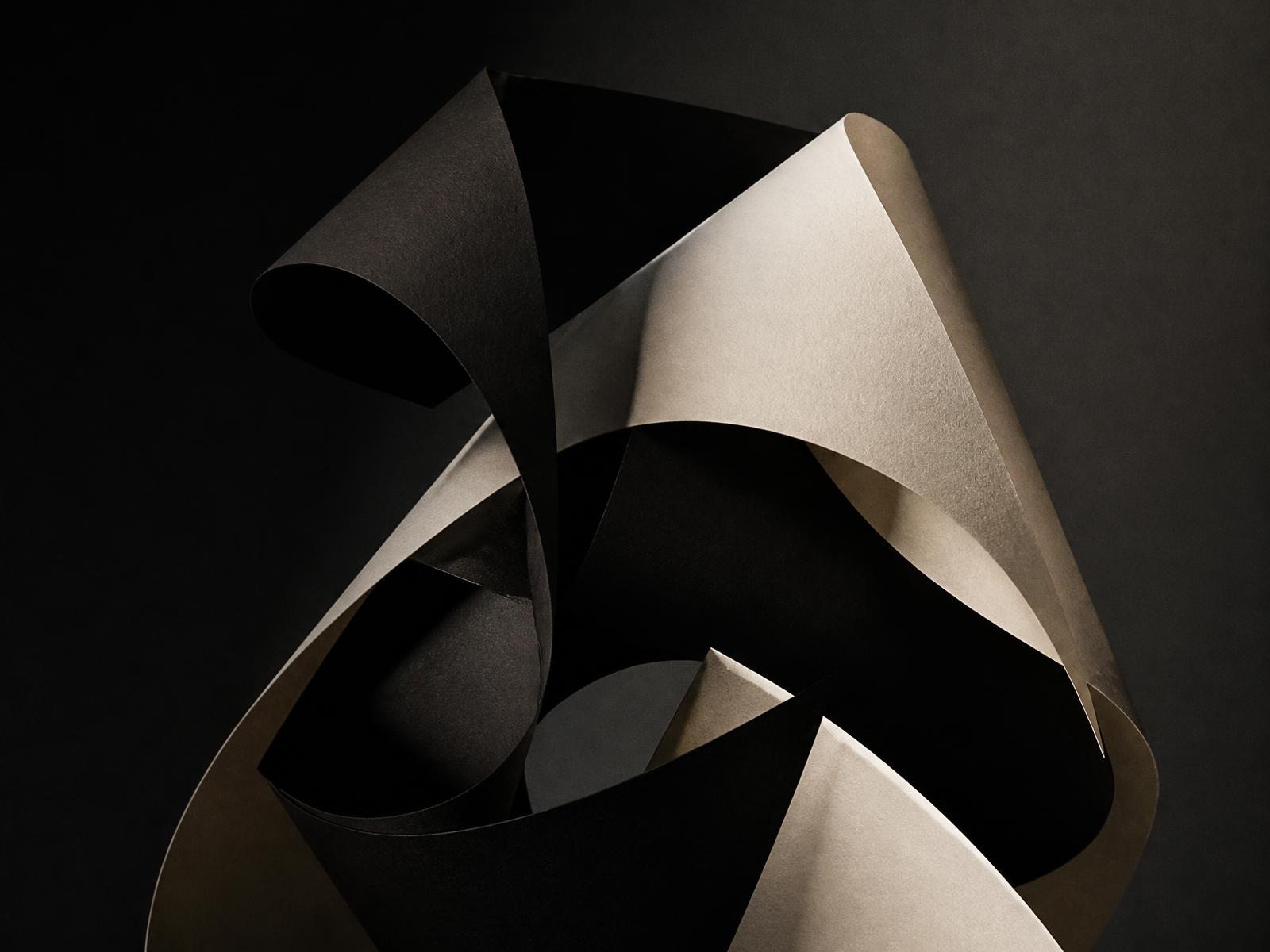 Sculptural folded paper forms lit in dramatic studio light